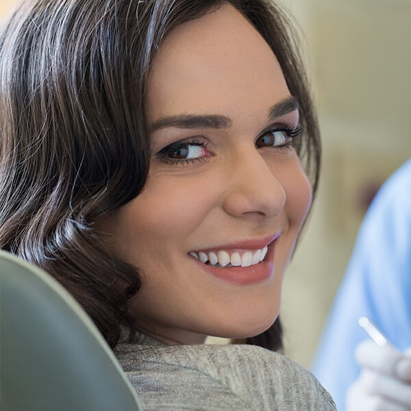 Learn more about our services Young woman sitting in the dentist's chair after her dental appointment