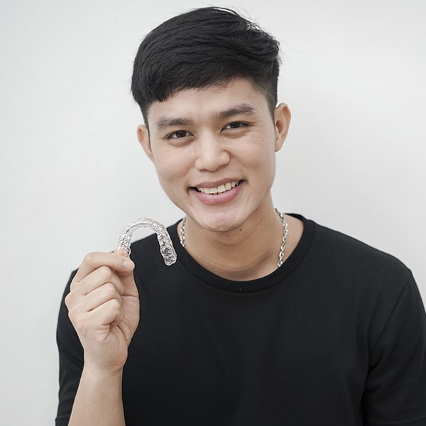 A young man holding his clear aligners 