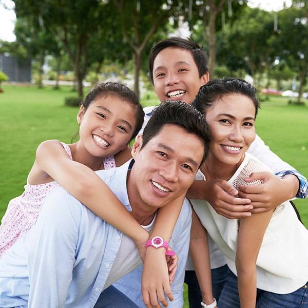 A family of four playing in the park while hugging