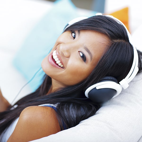See how porcelain veneers work with these three easy steps A young woman with porcelain veneers smiling while listening to music