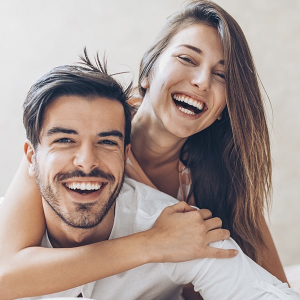 A young couple showing off their new smile after their porcelain veneers treatment