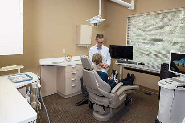 Dr. Alm explaining the treatment to his patient sitting in the dentist's chair