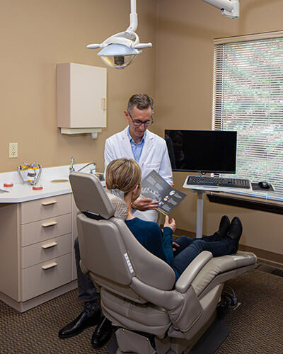 Dr. Alm explaining the dental procedure to his patient sitting in the dentist's chair